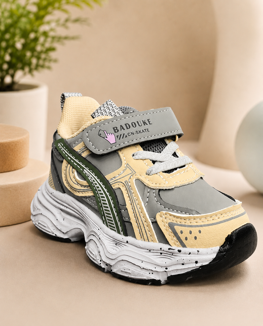 Kids retro chunky sneakers in grey, tan, and dark green with velcro strap, thick rubber sole, and mesh upper.