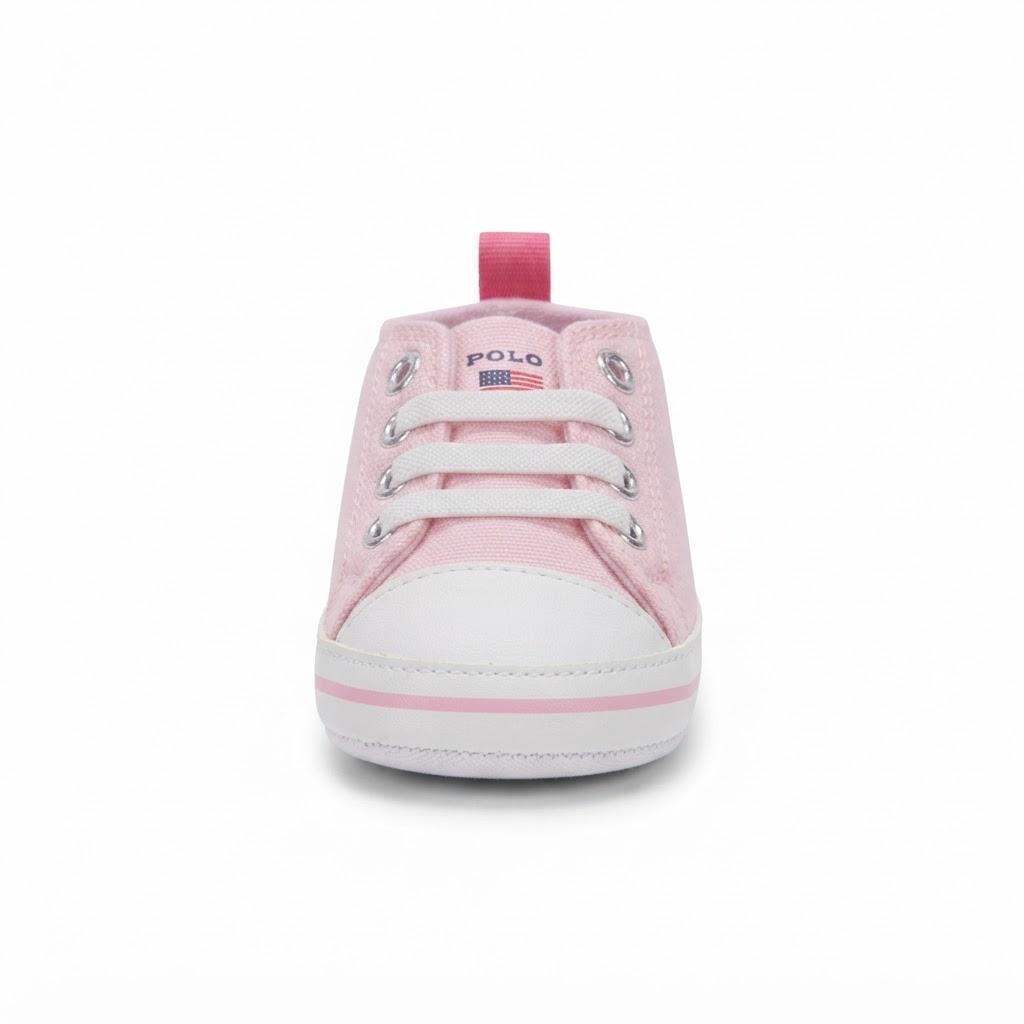 A light pink canvas baby sneaker with white laces, a white rubber toe cap, and a pink pull tab, shown from the front on a white background.