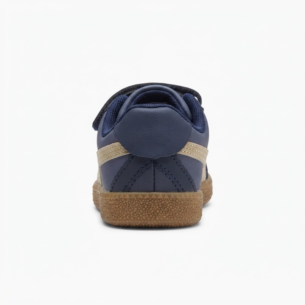 A single navy blue low-top sneaker shown from the rear three-quarter view, featuring a tan suede side stripe and a textured brown gum sole, set against a plain white background.