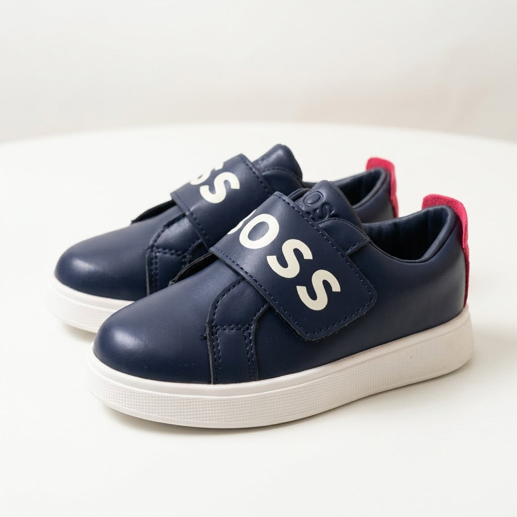 A pair of navy blue children's sneakers with white soles, photographed on a clean white surface.