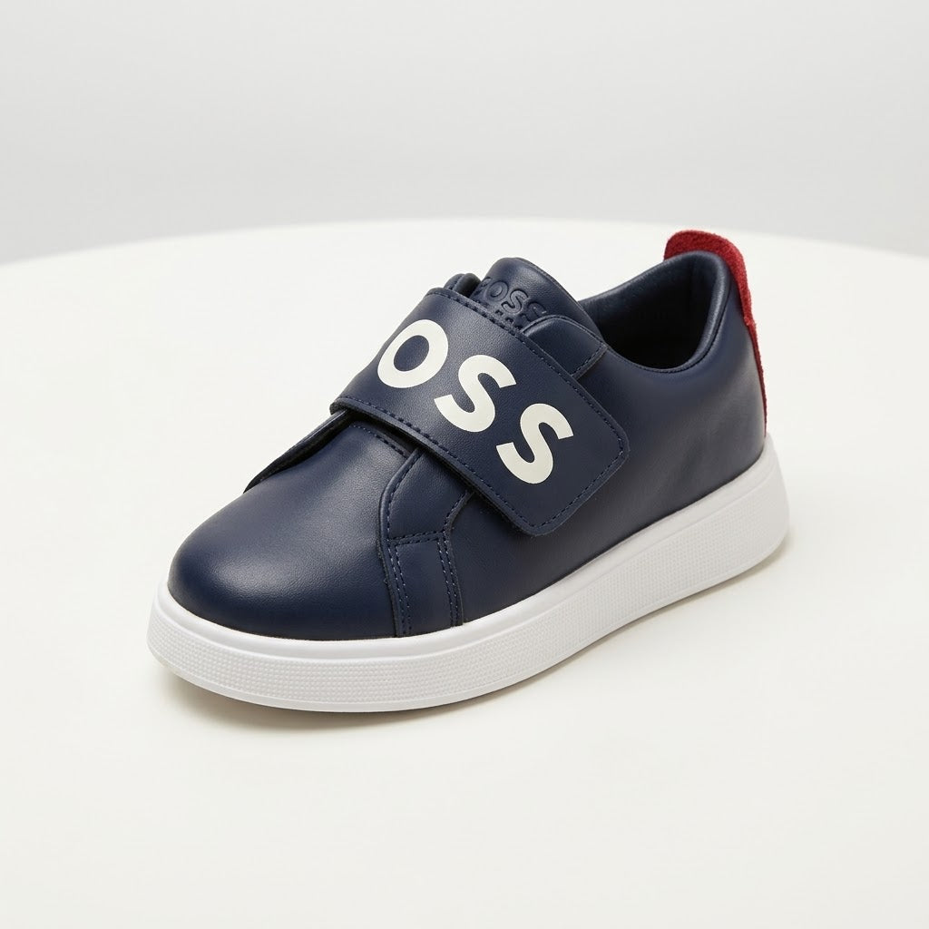 A navy blue leather slip-on sneaker and a red pull tab on the heel, set against a clean white background.