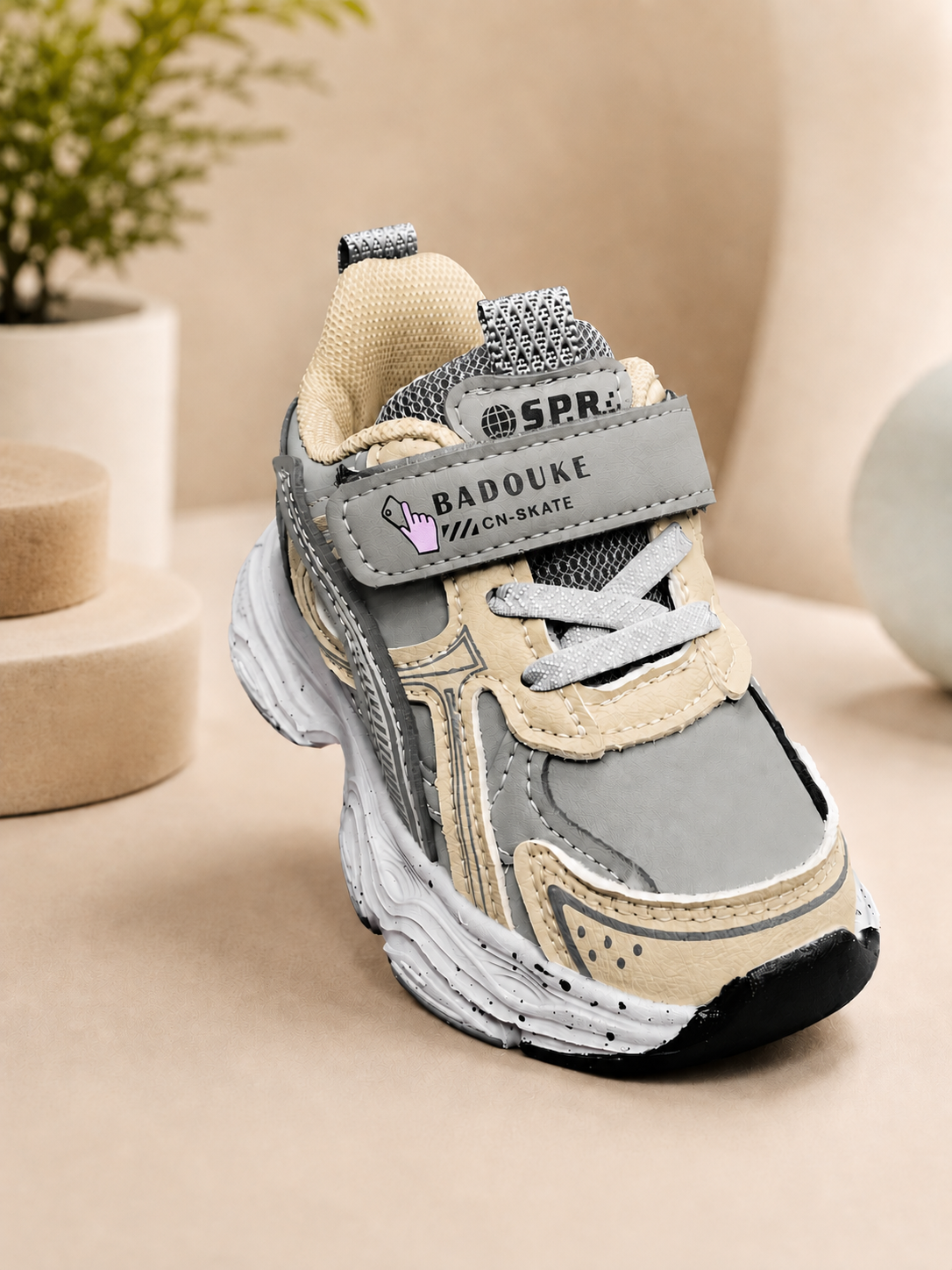 Kids retro chunky sneakers in grey, tan, and dark green with velcro strap, thick rubber sole, and mesh upper.