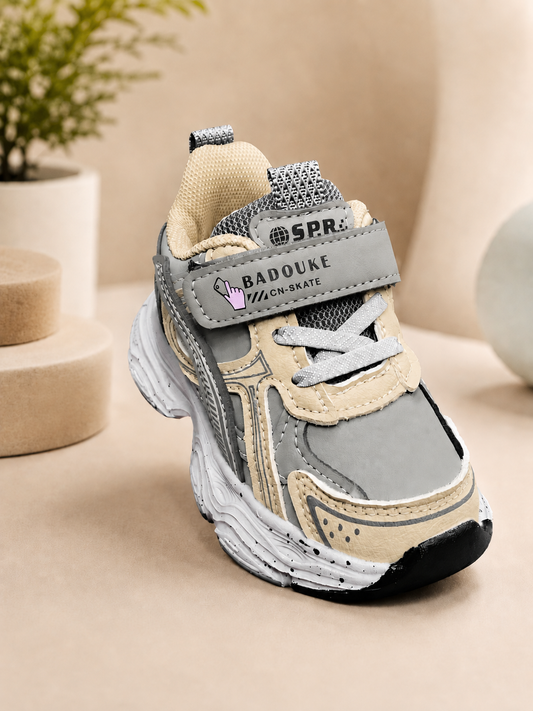 Kids retro chunky sneakers in grey, tan, and dark green with velcro strap, thick rubber sole, and mesh upper.