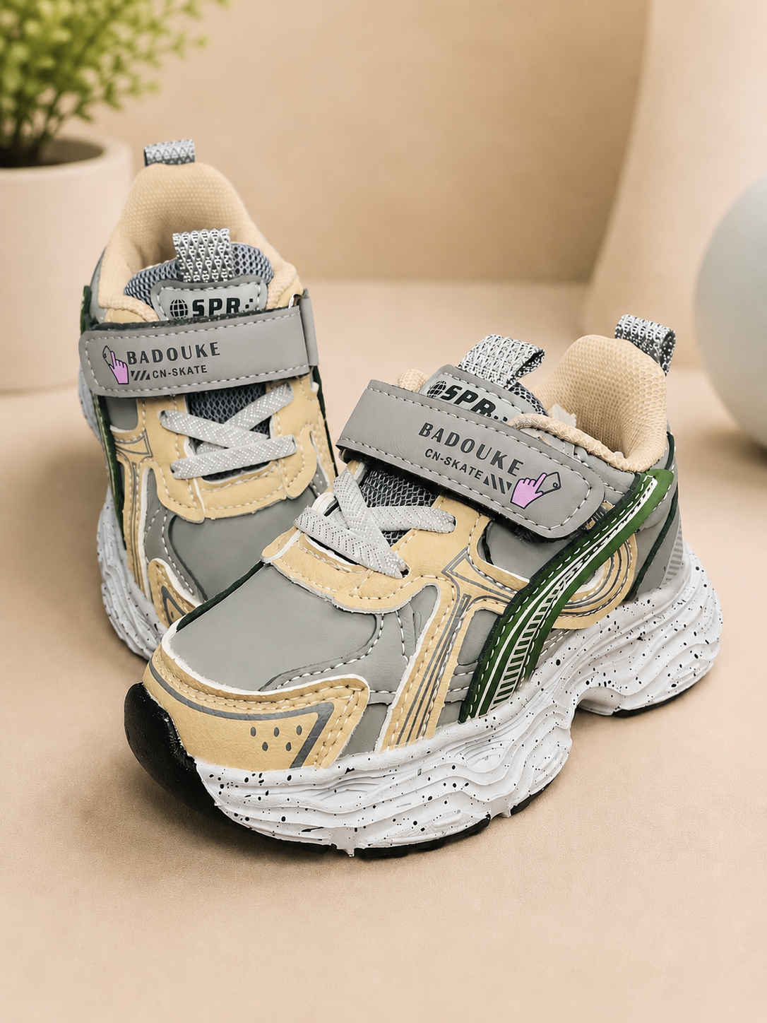 Kids retro chunky sneakers in grey, tan, and dark green with velcro strap, thick rubber sole, and mesh upper.