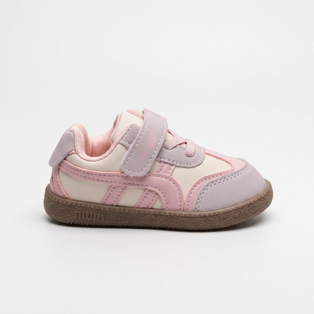 A toddler's low-top sneaker in light pink and cream, featuring a hook-and-loop strap closure and a brown rubber sole, shown from the side on a light gray background.