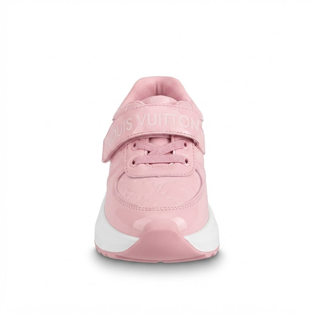 A pink sneaker shown from the front on a clean white background. The shoe features a pink upper with a hook-and-loop strap across the top, a white midsole, and a glossy pink toe cap.